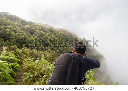 Photographer taking photo on the top of mountain; above the clouds at the Doi Inthanon is the highest mountain in Thailand. It is in Chom Thong District, Chiang Mai