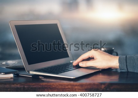 Male typing on keyboard with one hand on blurry background with sunlight