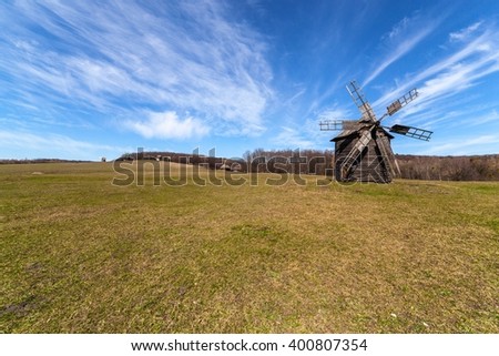 Rural landscape: windmill, field and cloudy sky.