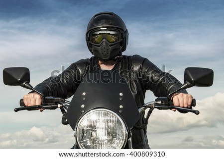 Motorbiker on motorbike with black helmet reflection of countryside in visor leather jacket blue sky white clouds with hands on handle bars stock photography