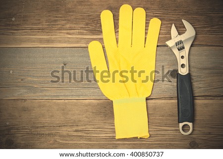 yellow glove and adjustable spanner on the wooden surface of the old bench. copy space. instagram image filter retro style