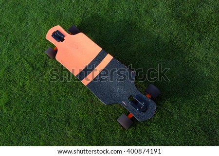 longboard grass green. Black and orange longboard on a green lawn grass