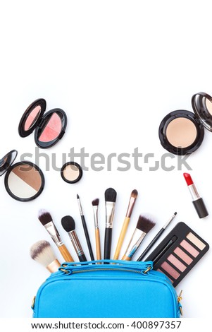 Flat lay photo of makeup bag with various brush and cosmetics on white background, top view