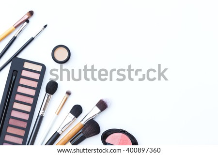Flat lay photo of makeup brush and cosmetics on white background, top view