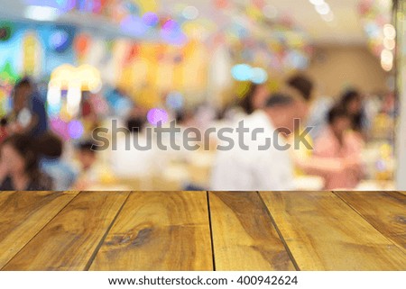 blurred image wood table and abstract people in food center with light bokeh