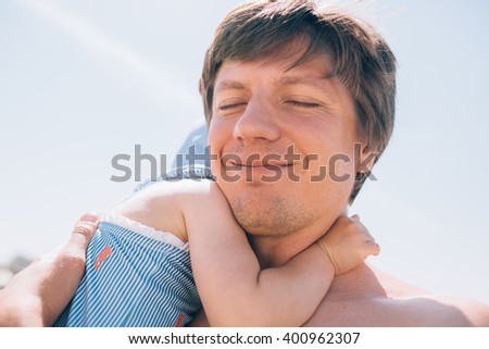 Cute little toddler baby daughter hugging her father outdoors at the beach