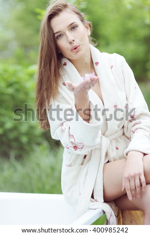 Young beautiful girl sitting on the edge of a bath in the garden