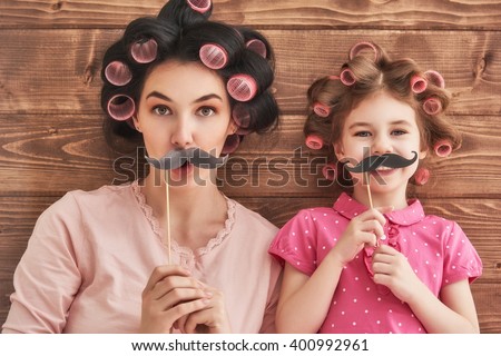 Funny family! Mother and her child daughter girl with a paper accessories. Beauty funny girl holding paper mustache on stick. Beautiful young woman holding paper mustache on stick. Royalty-Free Stock Photo #400992961