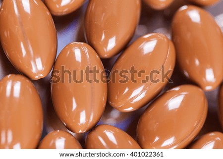 a scattering of brown capsules, tablets on a mirrored background, macro, picture with depth of field
