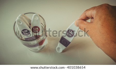 Retro styled or retro color medication tablespoon or pharmaceutical spatulas with clear transparent glass on empty background. Slightly de-focused and close-up shot.