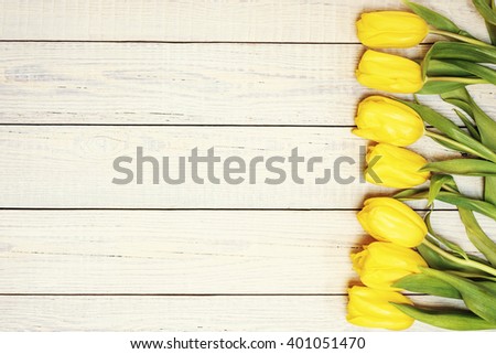Fresh yellow tulips on wooden background. Top view. Photo with retro filter effect.
