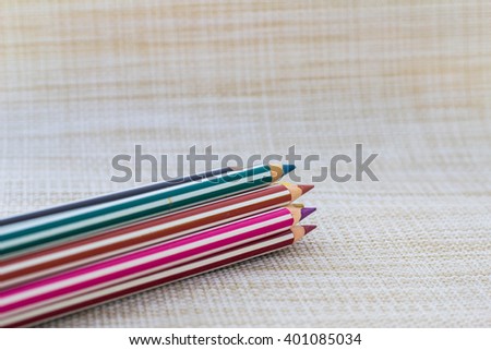 Striped colour pencil grouped together on textured background. Selected focus.