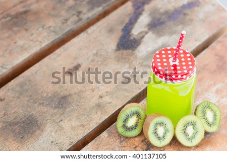 Green juice and kiwi slices on a wooden table, horizontal photo