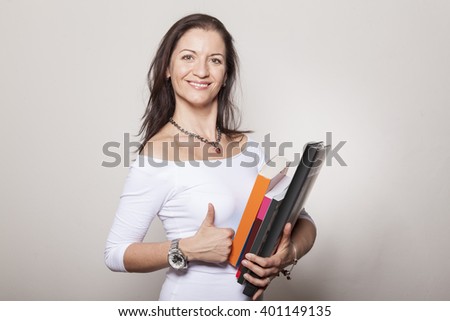 Female adult student with several books holds up thumb smiling happily Royalty-Free Stock Photo #401149135