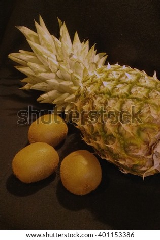 Royalty Free Photograph - Three Kiwi Fruit & One Ripe Fresh Pineapple are Isolated on Black Fabric Background