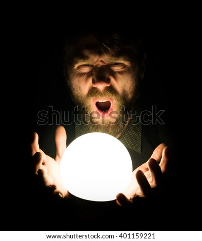 close-up of a bearded man expresses various emotions on a black background, holding a lamp in front of himsalf