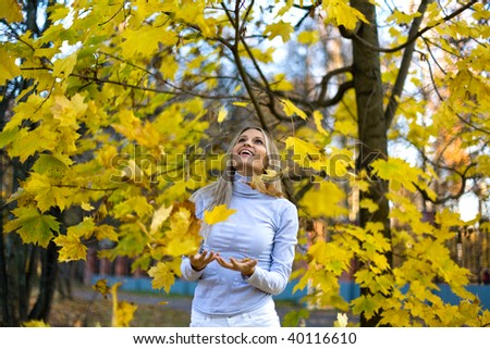 happy woman in the autumn park are catching falling leaves.