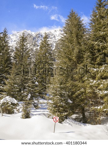No trespassing sign on wooden pole in snow, forest in Tatra Mountains, Poland.