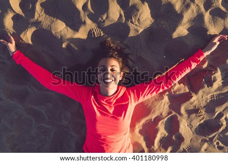Young beautiful runner lying on sand in the beach