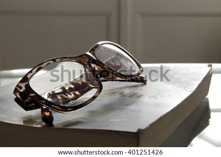 Glasses are laying on a book . Short focus picture. Focus on glasses.