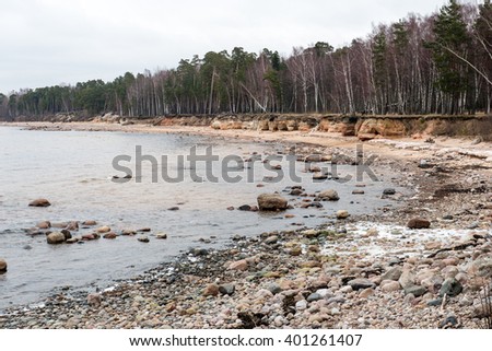 Rocky autumn beach with waves crashing on the rocks in misty weather