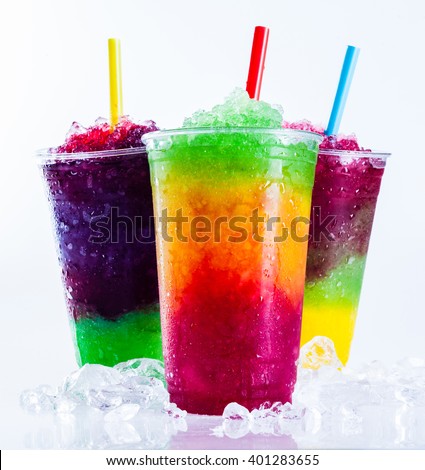 Still Life Close Up of Colorful Rainbow Layered Frozen Fruit Slush Drinks Arranged on Ice Covered White Surface in Plastic Take Away Cups with Drinking Straws - Trio of Refreshing Granitas Royalty-Free Stock Photo #401283655