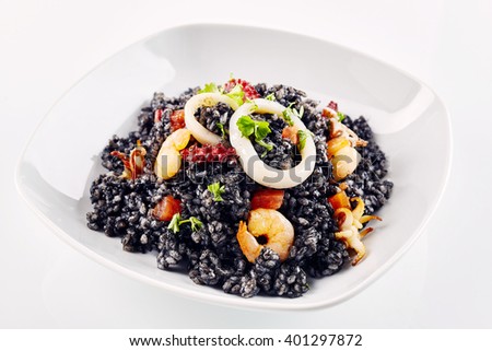 Close up of freshly prepared Arroz Negro garnished with various types of seafood in white dish