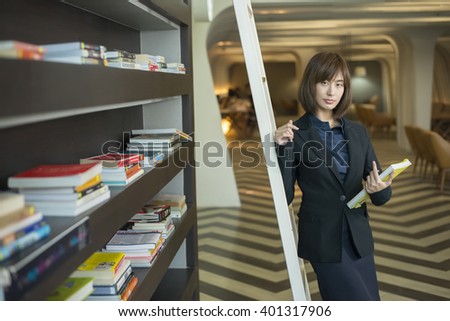 Attractive asian business woman with a book in the library