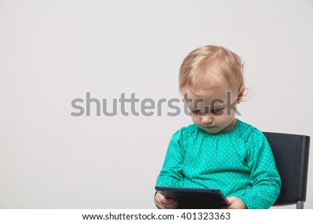 Infant child baby girl toddler sitting and typing digital tablet mobile computer isolated on a white background
