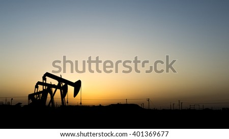 Sunset and silhouette of crude oil pumping unit in oil field - Bahrain