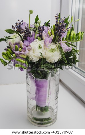 Beautiful spring bouquet of wedding flowers buttercup ranunculus, fresia, lavender in vase with violet tape. Pastel colors. Rustic style, still life. Holiday present on white Background.