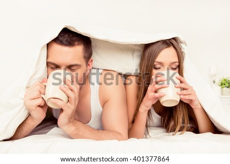 Close up portrait of two lovers drinking tea under blanket