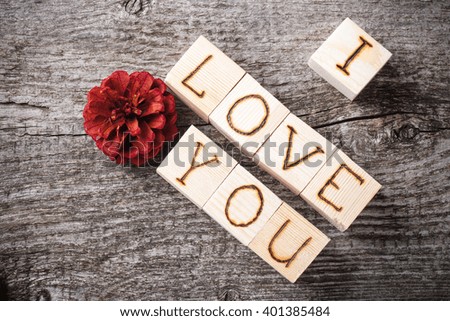 Romantic inscription of letters on light wooden cubes on a old grey wooden background. Toned.