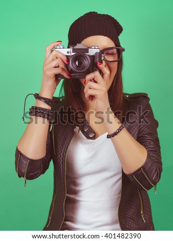 Cool hipster girl taking a picture with old vintage camera. On green screen