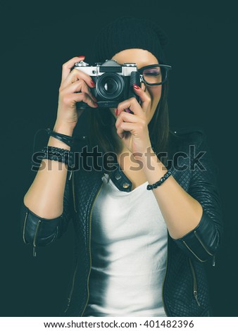 Cool hipster girl taking a picture with old vintage camera. On black screen