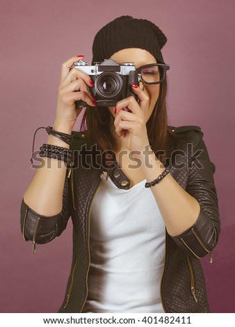 Cool hipster girl taking a picture with old vintage camera. On brown red screen