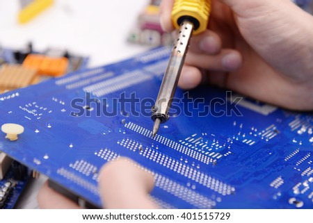 Young repairer working with soldering iron in service center