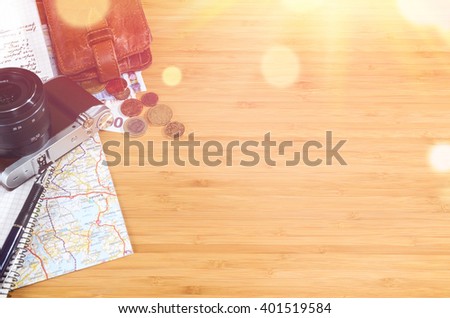 getting ready for travel, money, map and photo camera on wooden table with copy space and sun flare