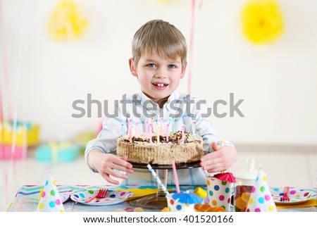 Happy little boy with tasty cake at birthday party