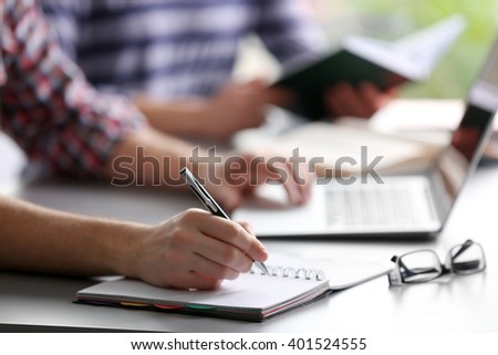 Student's hand writing in exercise book at the table Royalty-Free Stock Photo #401524555