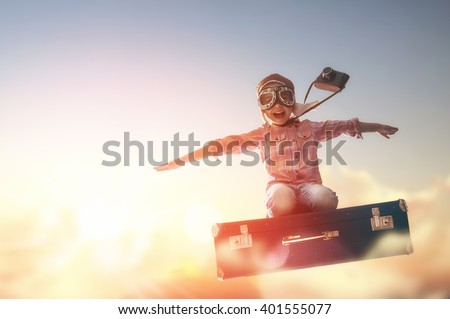 Dreams of travel! Child flying on a suitcase against the backdrop of a sunset. Royalty-Free Stock Photo #401555077