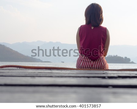 Girl sitting on wood balcony, with sea and mountain, travel background