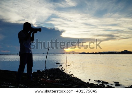 Silhouette image of photographer at lake with sunrise background:select focus with shallow depth of field.