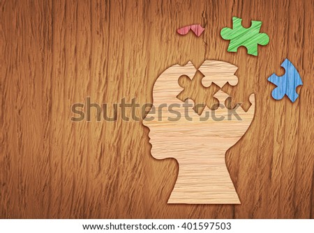 Mental health symbol. Human head silhouette with a puzzle piece cut out on the wooden background