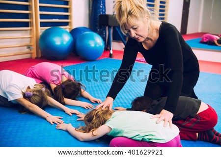 Corrective gymnastics - Physical therapist working with group of children, exercising spinal flexibility, improving body posture, positively influencing growth and development