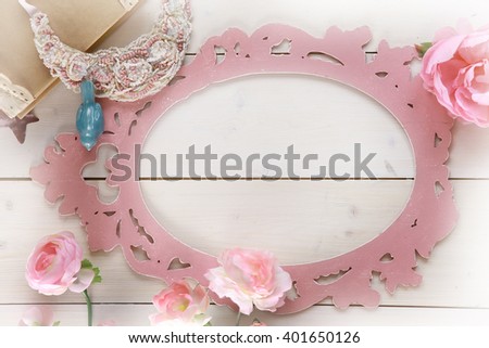 top view of the Desk of white wood. in the centre rose figured frame surrounds a place for a label. the edges of the book, a ceramic bird, pink peony, beaded decoration