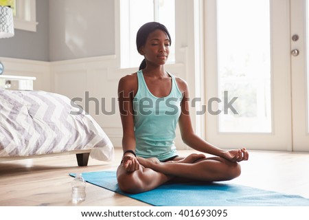 Young black woman doing yoga at home in the lotus position Royalty-Free Stock Photo #401693095