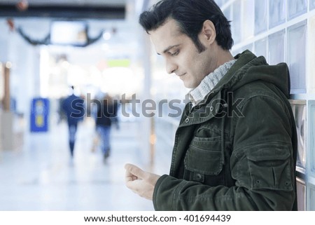 Young man ignoring the environment being addicted to social media. Conceptual image with people pretending that are always using phones or tablets in normal life.