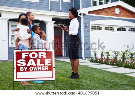 Estate agent and family outside house with a Ã¢??for saleÃ¢?? sign