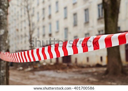 Red and white danger tape in front of house to be demolished                     
